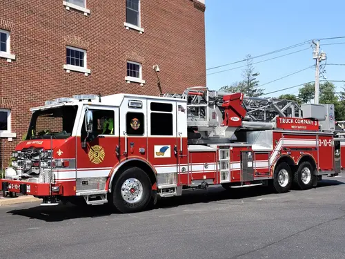 Tower ladder truck front-left exterior view parked by brick building