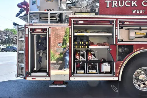 Open side compartment showing tools and equipment shelves near rear axle