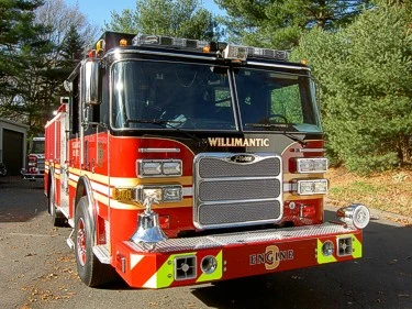 Head-on front view of a red pumper showing grille, bumper intake ports, warning lights, and windshield.