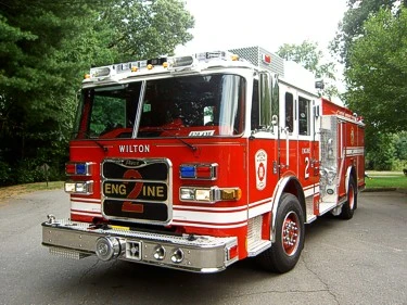 Pumper front-left exterior view showing enclosed cab, bumper, and side compartments