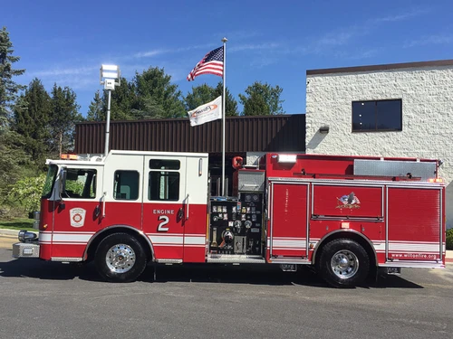 Full right-side profile of a red-and-white pumper showing pump panel, compartment doors, and wheel/tire areas.
