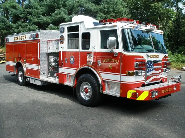 Front-right exterior view of a rescue pumper showing the cab, bumper, pump panel, and side compartments.