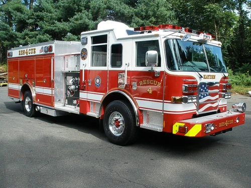 Front-right exterior view of a rescue pumper showing the cab, bumper, pump panel, and side compartments.