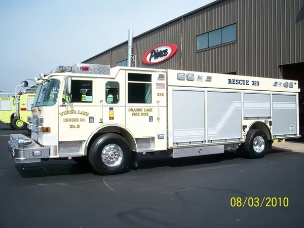 Driver-side profile of a rescue truck with enclosed cab, long side compartments, and rear wheel area.