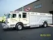 Wide driver-side view of the rescue truck parked at the plant with full body length visible.
