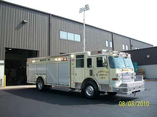 Front-right wide view of the rescue truck outside the bay with side compartments visible.