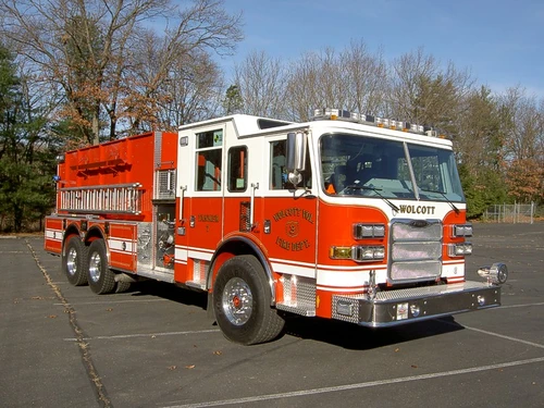 Front-right exterior view of a tanker showing enclosed cab, side pump panel section, and tandem rear axles.