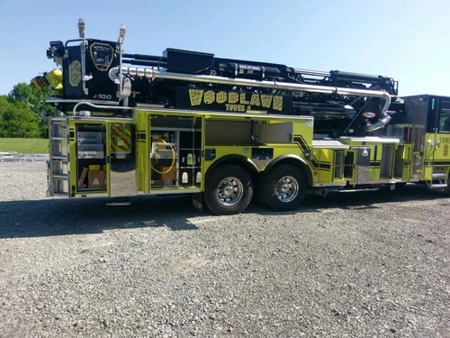 Driver-side mid-body view showing open compartments and tandem axles