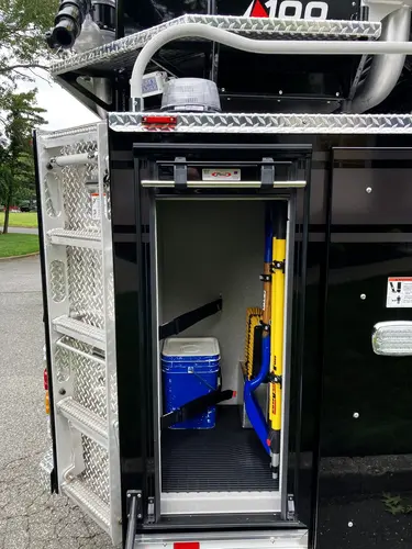 Rear-side vertical compartment open showing cooler and long-handled tools