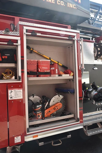 Open side compartment showing trays with rescue saws and hand tools
