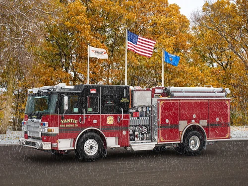Yantic fire engine driver-side profile in snowfall showing pump panel and side hose bed