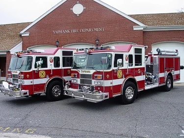 Front-left lineup view of two pumpers parked in front of the Yaphank fire station.