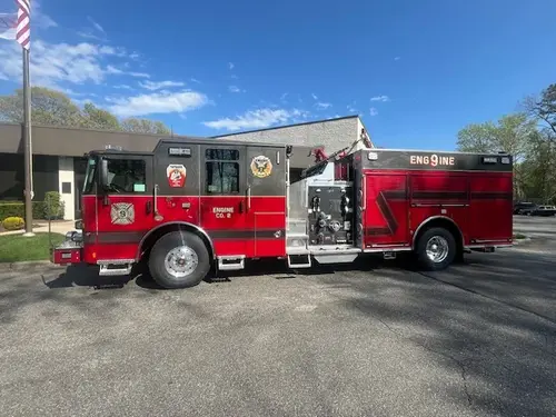 Pierce Enforcer top-mount pumper, driver-side profile view showing pump panel and side compartments