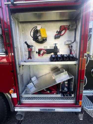 Open equipment compartment showing mounted cordless rescue tools and chargers