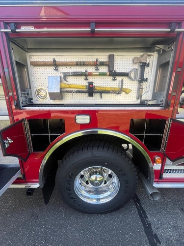 Open side compartment with mounted hand tools beside rear wheel and tire