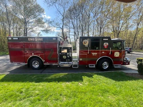 Pierce Enforcer top-mount pumper, officer-side profile view with side compartments and pump panel
