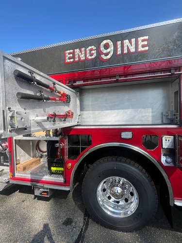 Open side compartment with mounted hand tools, rear wheel, and lower storage bay